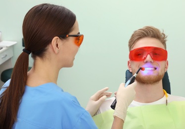 Photo of Professional dentist working with patient in modern clinic. Teeth whitening