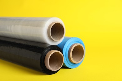 Photo of Rolls of different stretch wrap on yellow background, closeup