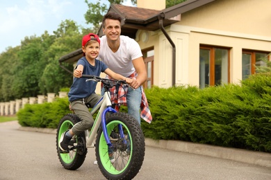 Dad teaching son to ride bicycle outdoors