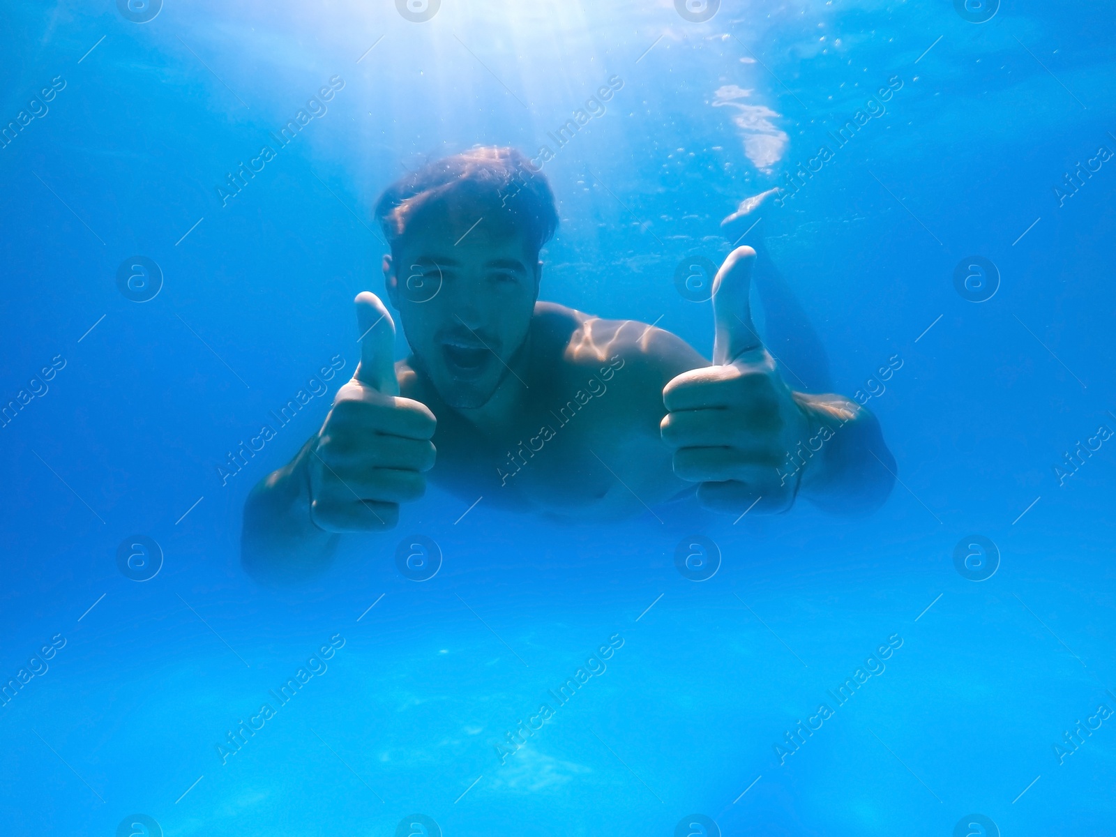 Photo of Handsome young man swimming in pool, underwater view