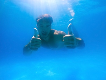 Handsome young man swimming in pool, underwater view