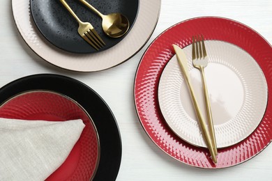 Stylish ceramic plates, cutlery and napkin on white wooden table, flat lay