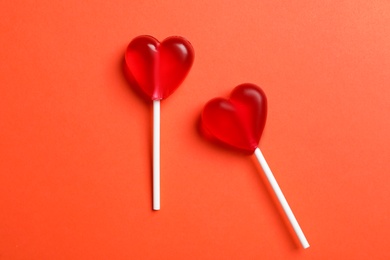 Photo of Sweet heart shaped lollipops on coral background, flat lay. Valentine's day celebration