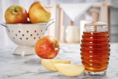 Photo of Jar of honey with tasty apples on marble table