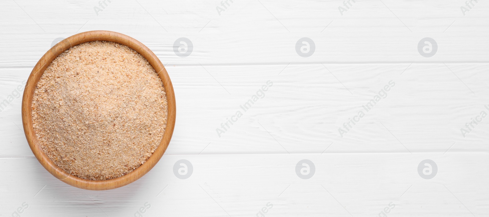 Photo of Fresh breadcrumbs in bowl on white wooden table, top view. Space for text