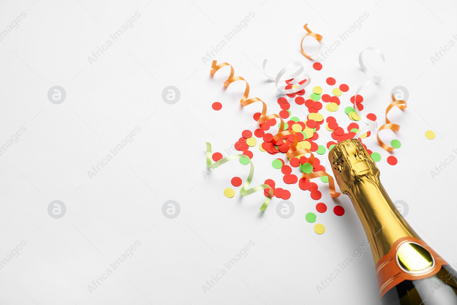 Photo of Composition with confetti and bottle of champagne on white background. Space for text