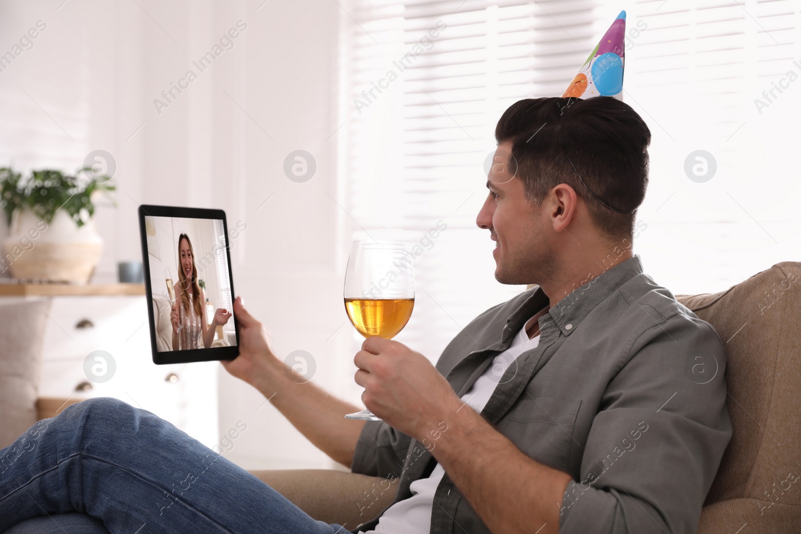 Image of Man with glass of wine having online party via tablet  at home during quarantine lockdown