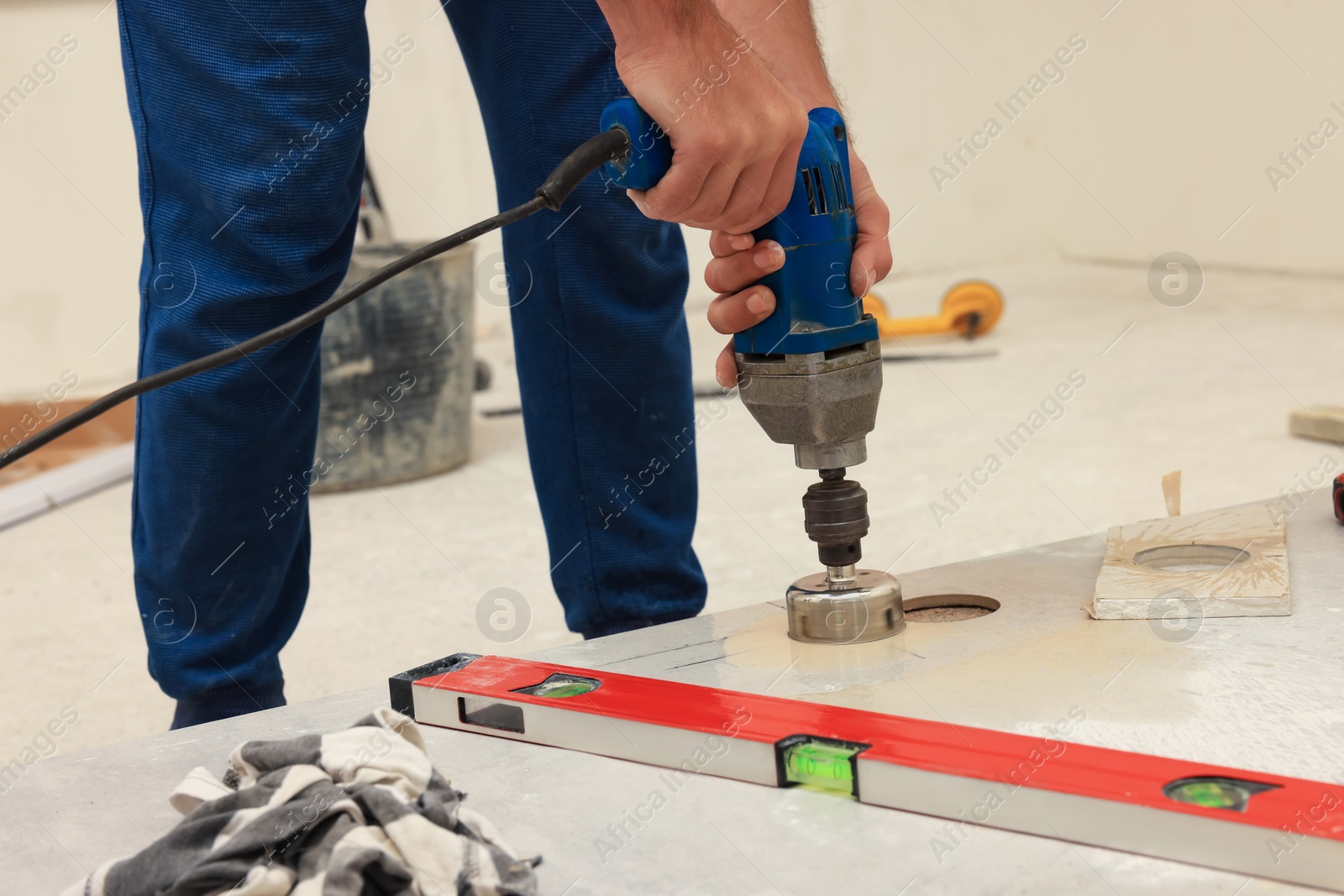 Photo of Worker making socket hole in tile indoors, closeup