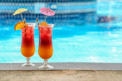 Glasses with tasty cocktails near swimming pool