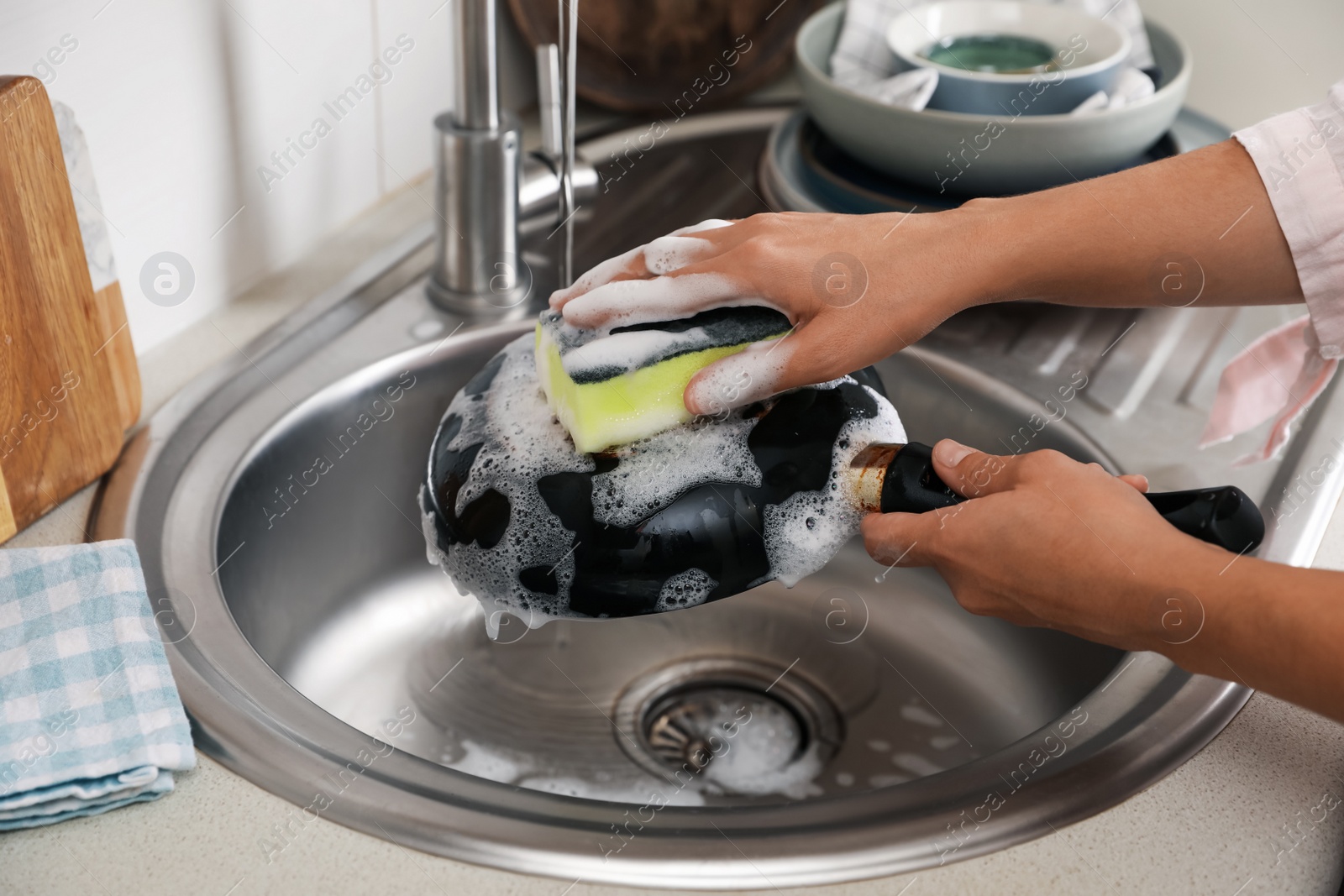 Photo of Woman washing dirty frying pan in sink indoors, closeup