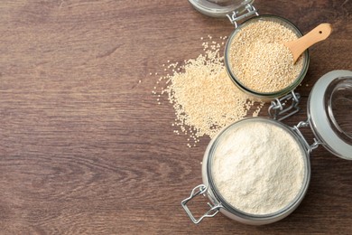 Photo of Jars with quinoa flour and seeds on wooden table, flat lay. Space for text