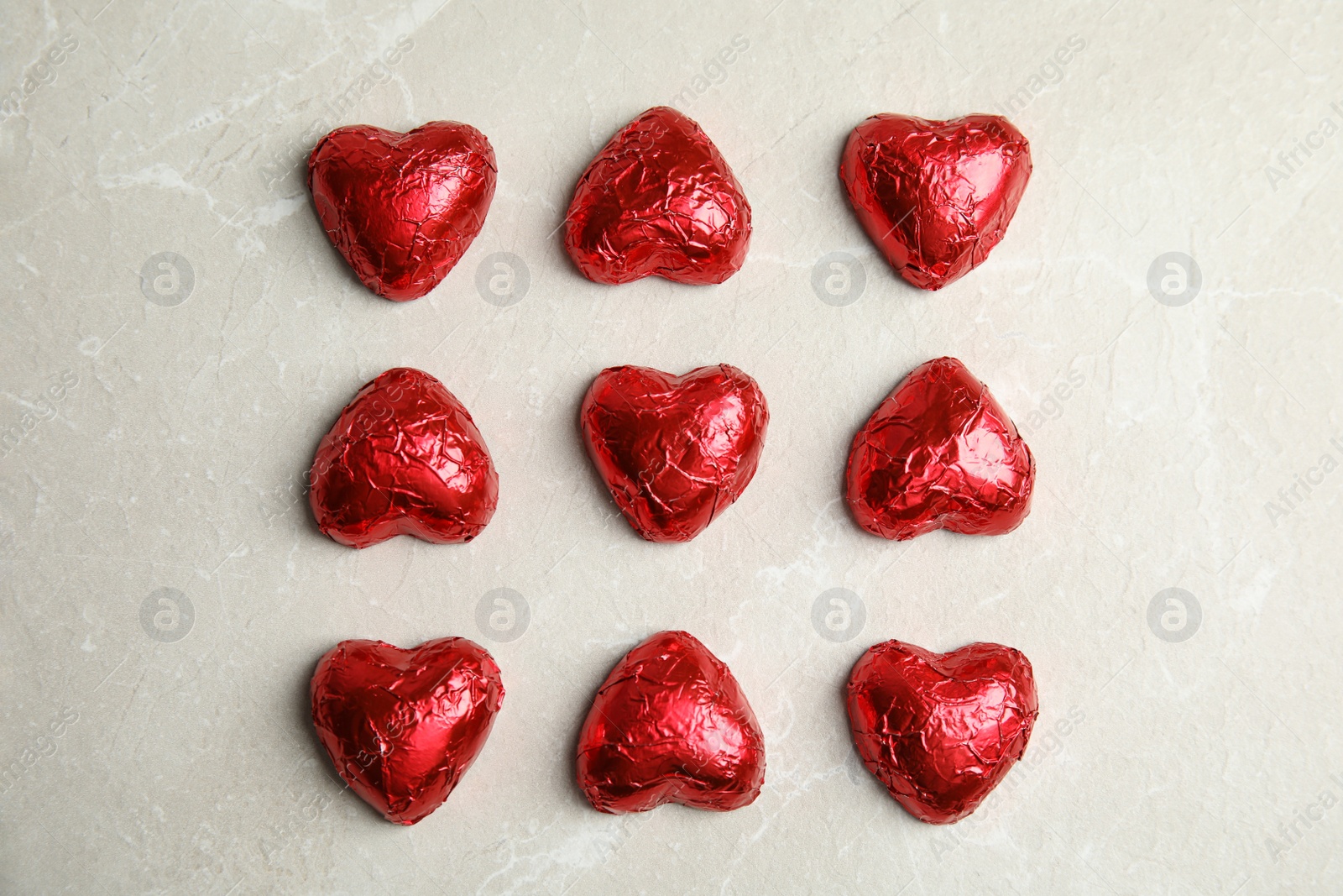 Photo of Heart shaped chocolate candies on light grey table, flat lay. Valentine's day treat