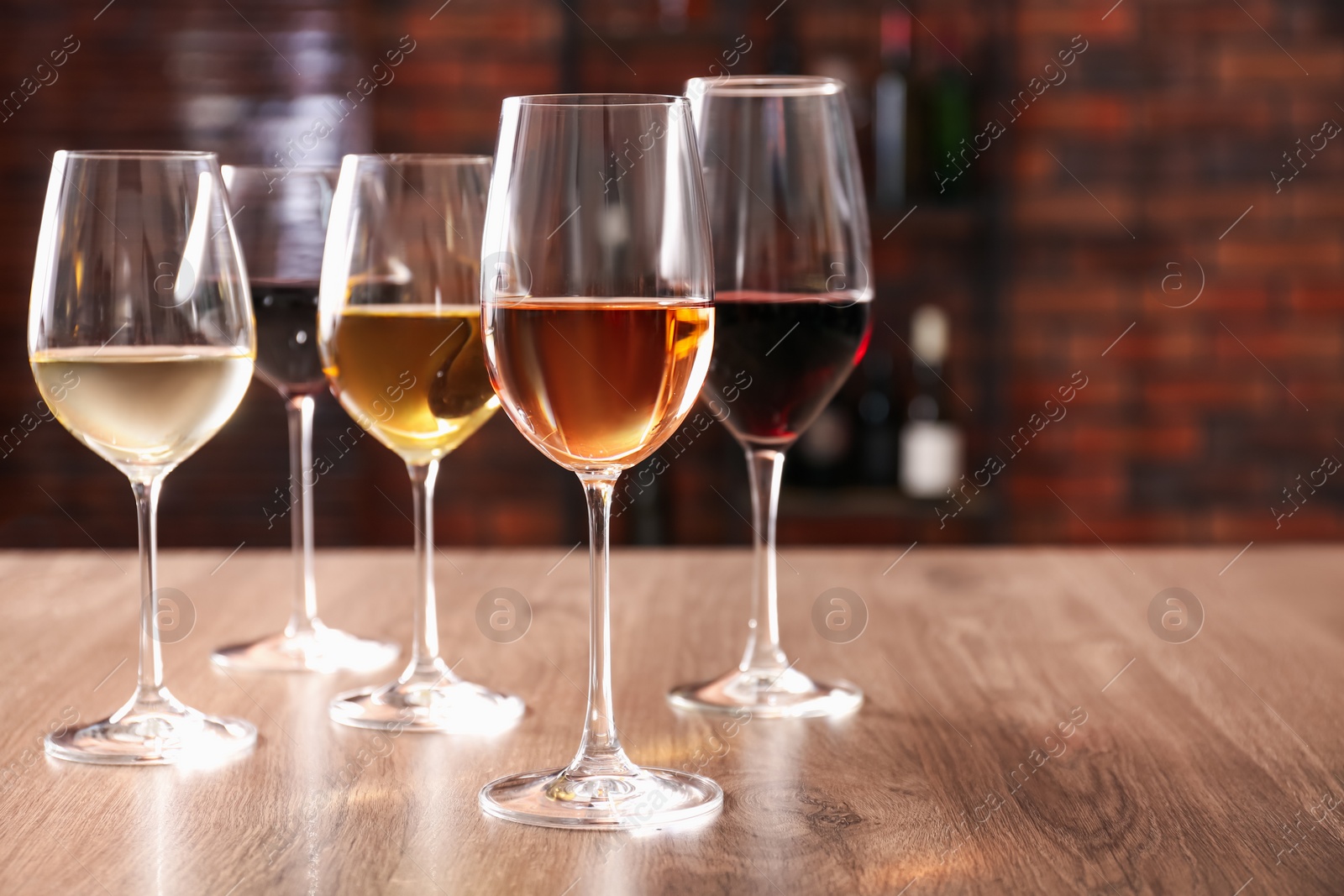 Photo of Different tasty wines in glasses on wooden table, space for text