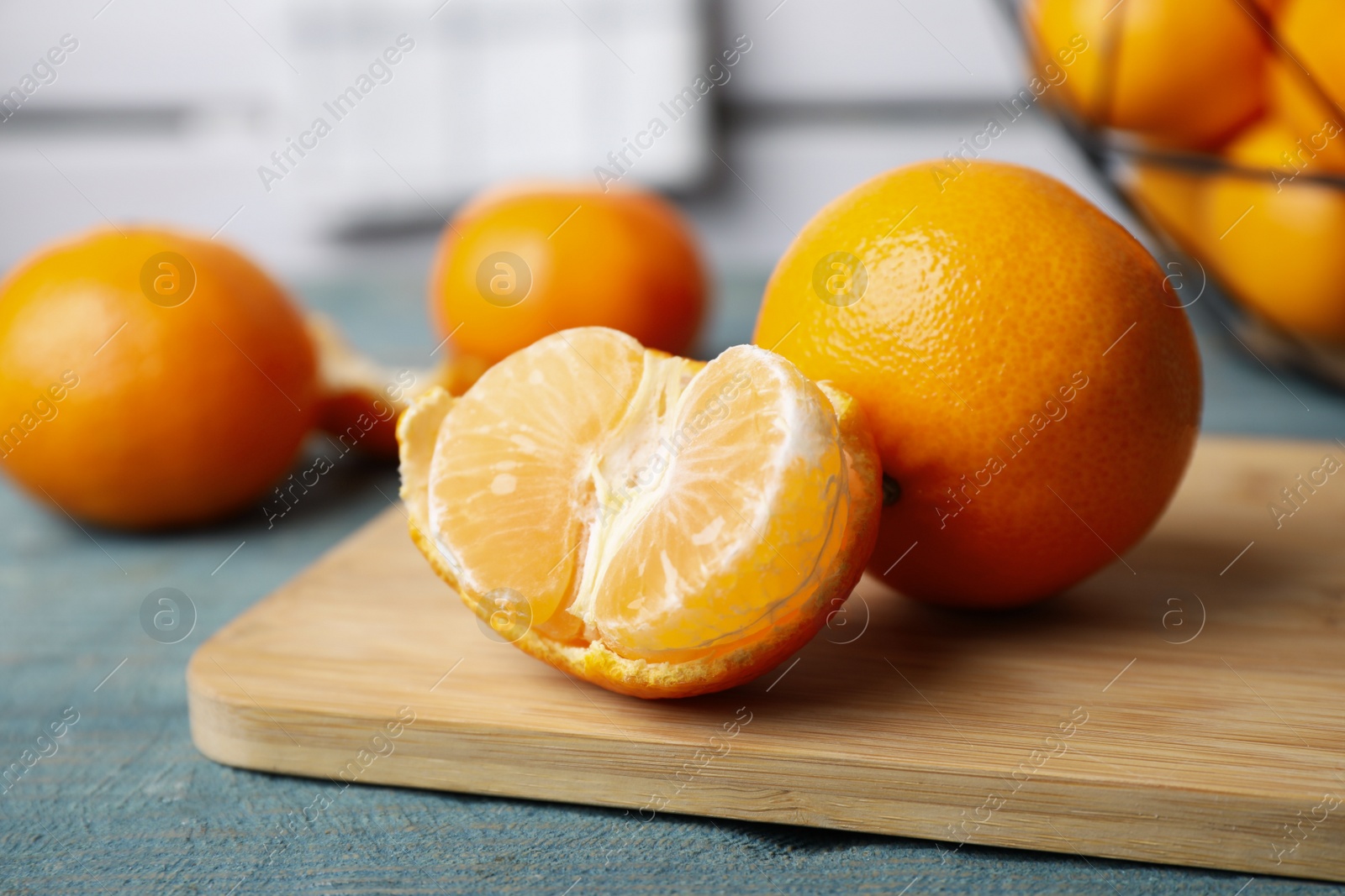 Photo of Fresh ripe tangerines on blue wooden table, closeup
