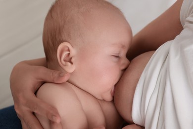 Photo of Mother breastfeeding her newborn baby on bed, closeup