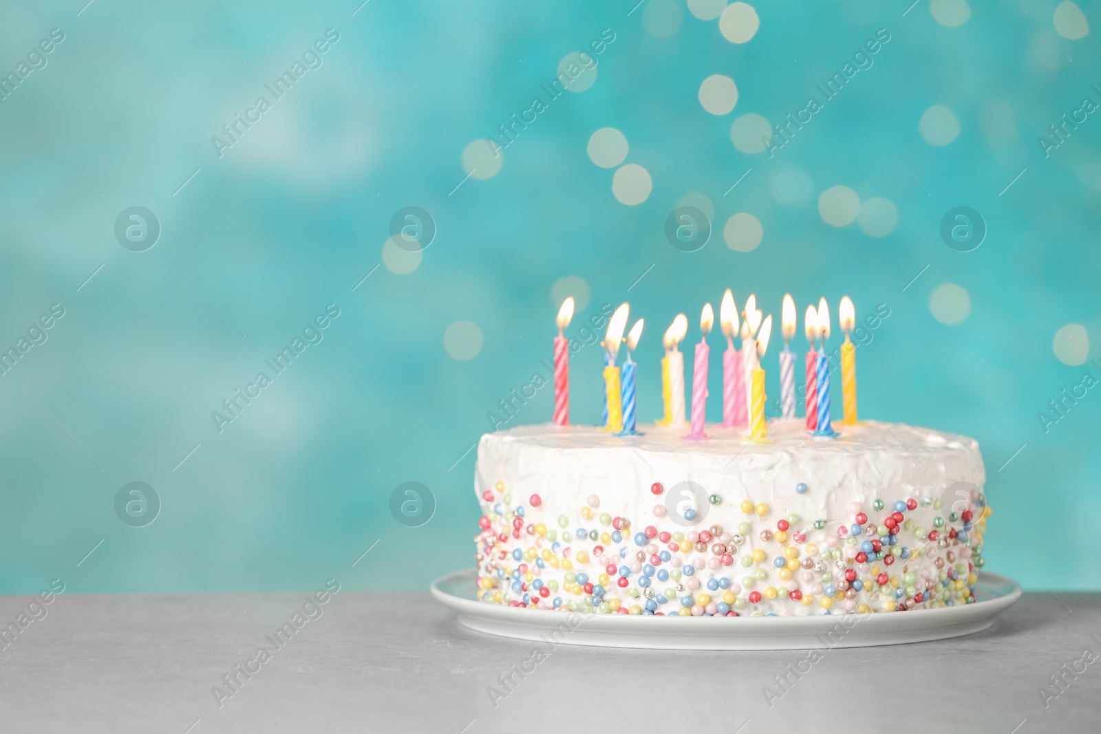 Photo of Birthday cake with burning candles on table against light blue background. Space for text