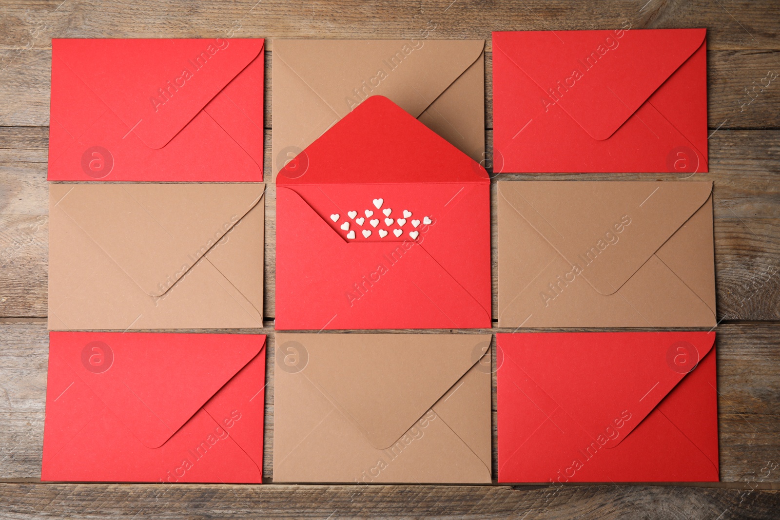 Photo of Envelopes and heart shaped sprinkles on wooden table, flat lay. Love letters