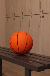 Photo of Orange basketball ball on wooden bench in locker room