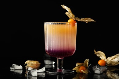 Photo of Refreshing cocktail decorated with physalis fruit on black background