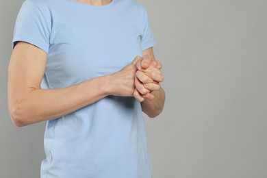 Woman cracking her knuckles on light grey background, closeup and space for text. Bad habit