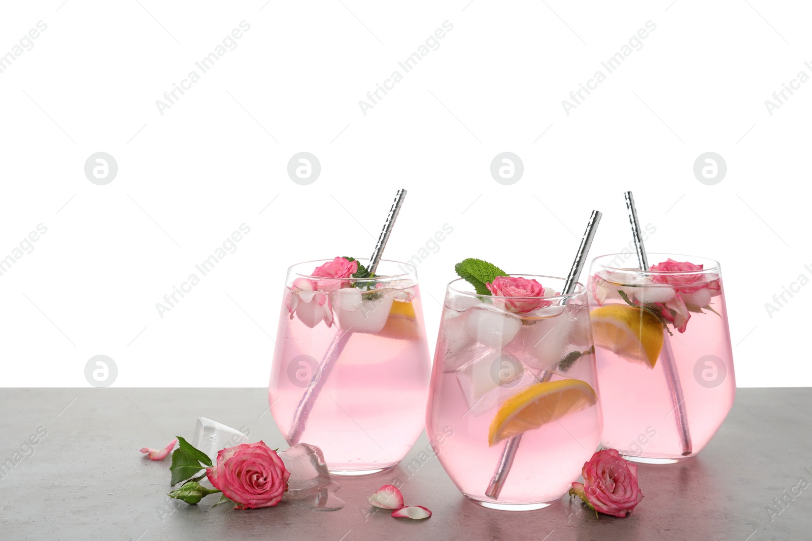 Photo of Delicious refreshing drink with rose flowers and lemon slices on light grey table against white background