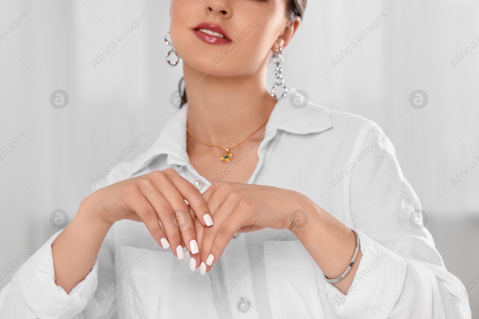 Photo of Beautiful woman with elegant jewelry on light background, closeup