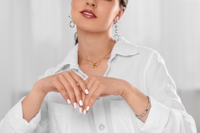 Photo of Beautiful woman with elegant jewelry on light background, closeup