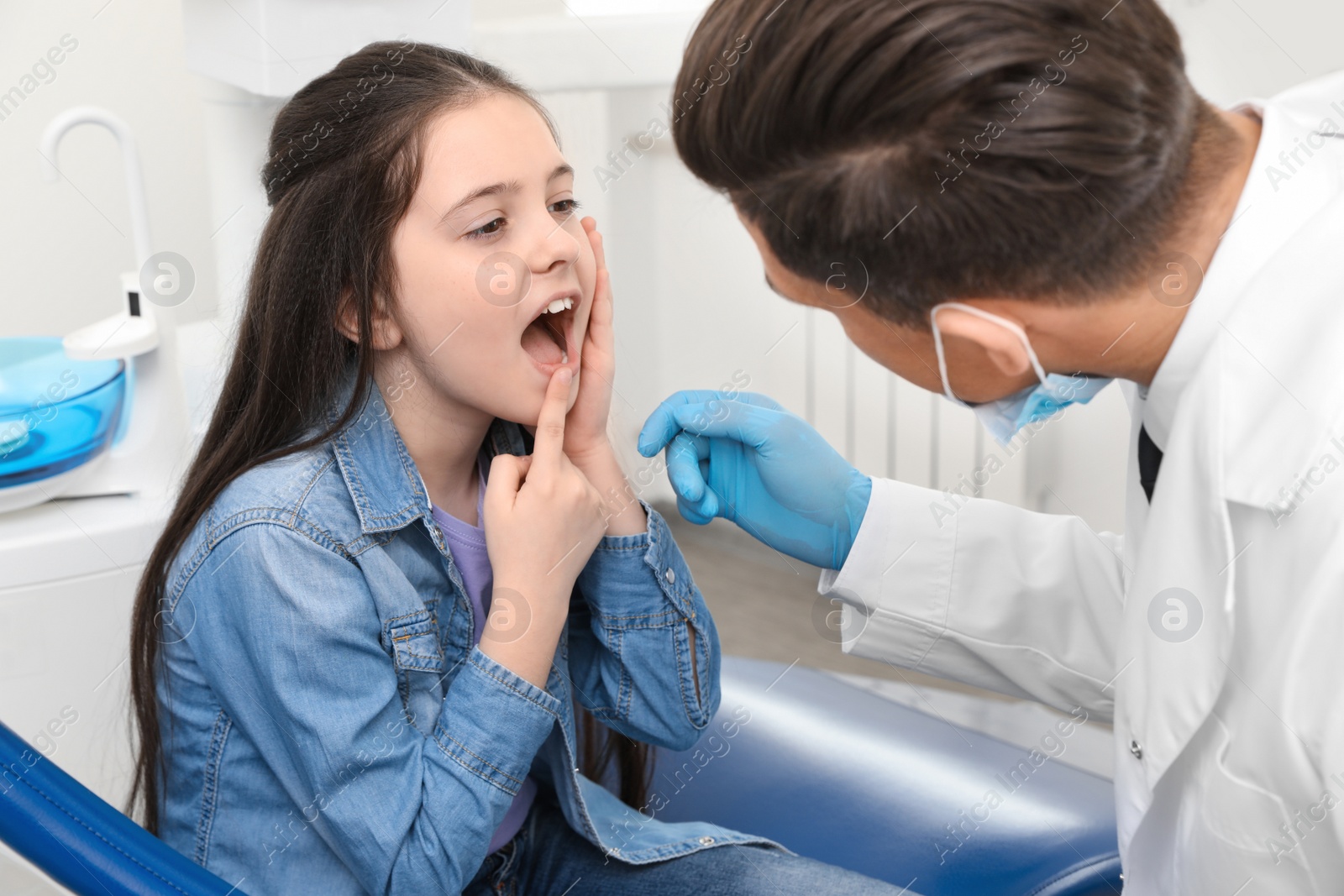 Photo of Professional dentist working with little girl in clinic