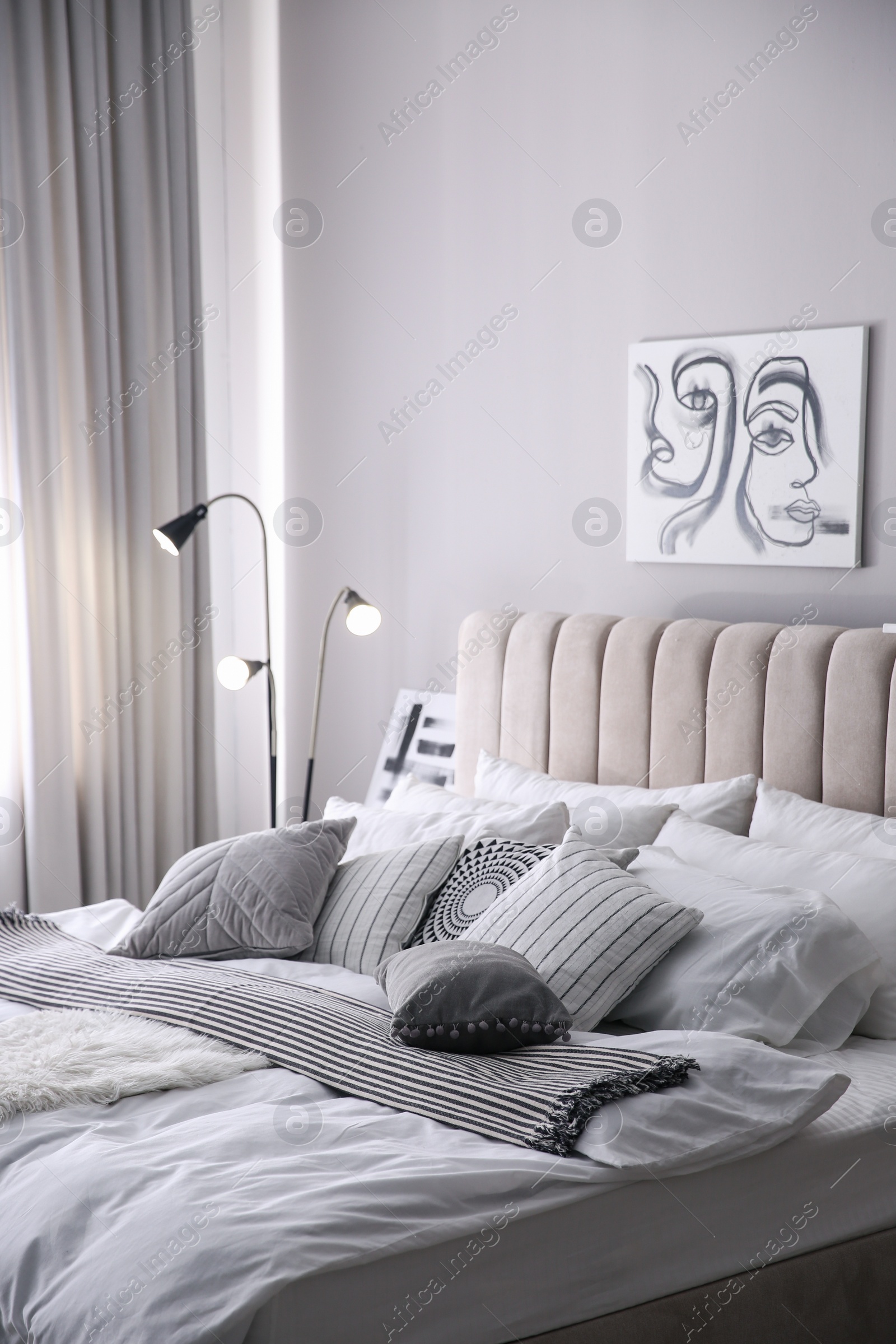 Photo of Cozy bedroom interior with cushions and striped blanket