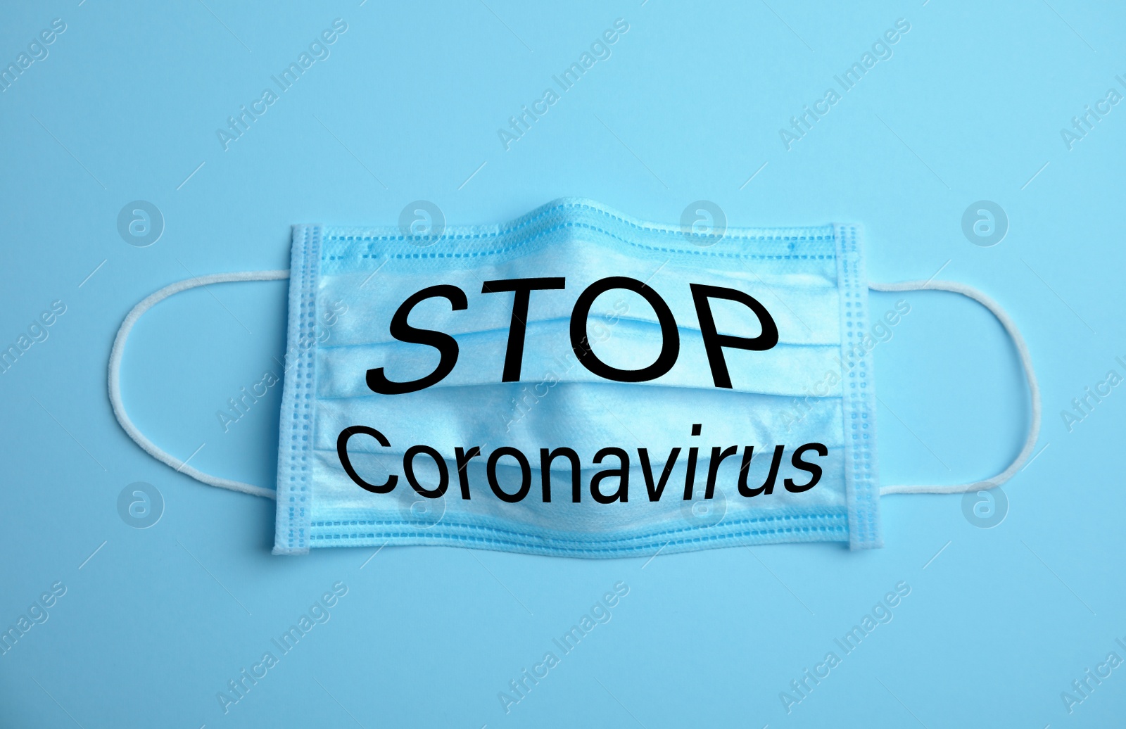 Image of Medical mask with text Stop Coronavirus on light blue background. Protective measures during pandemic