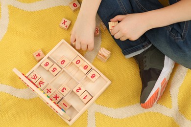 Photo of Child playing with math game kit on floor, top view. Learning mathematics with fun