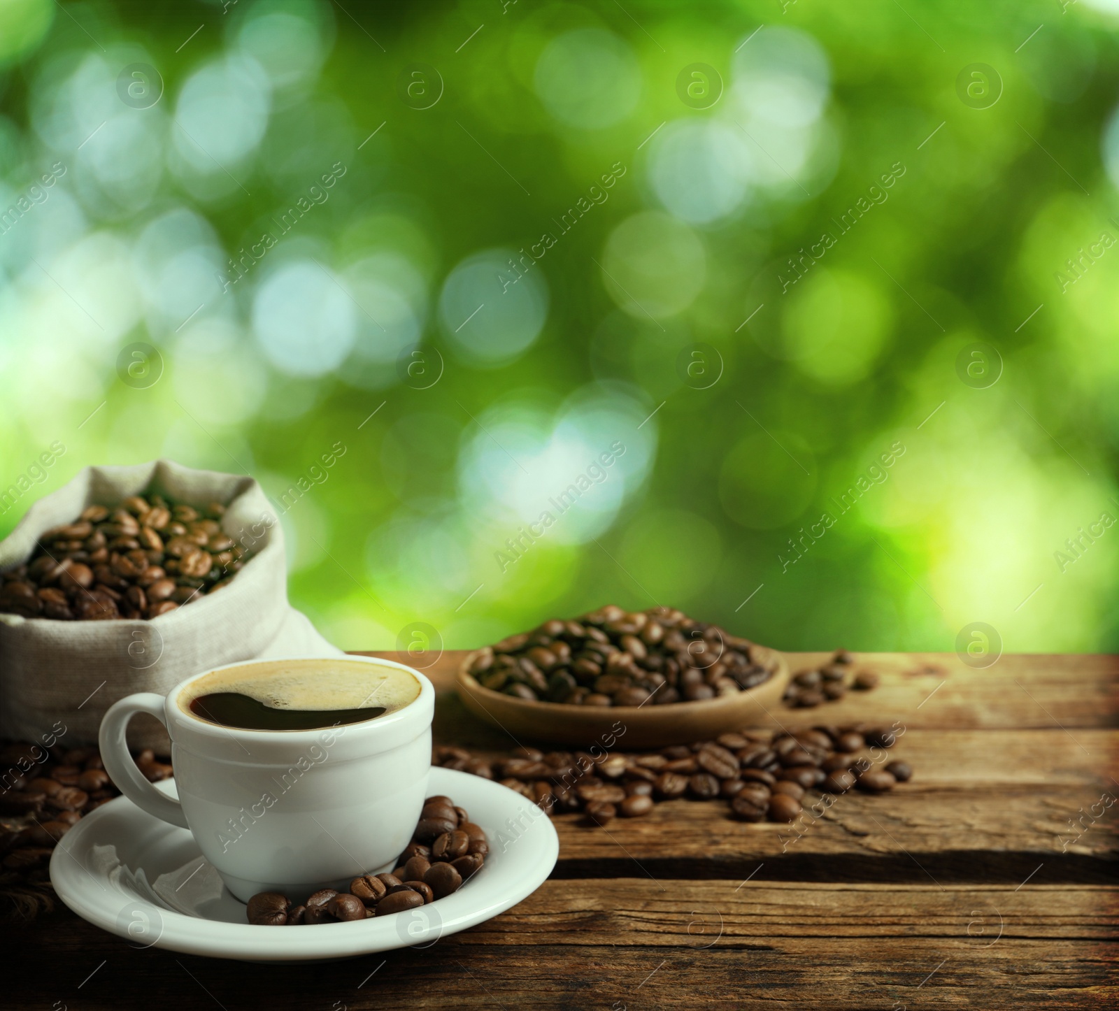 Image of Cup of aromatic hot coffee and beans on wooden table outdoors. Space for text