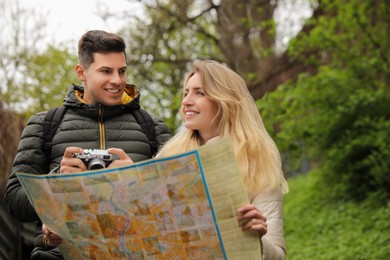 Photo of Couple of tourists with map planning trip in park