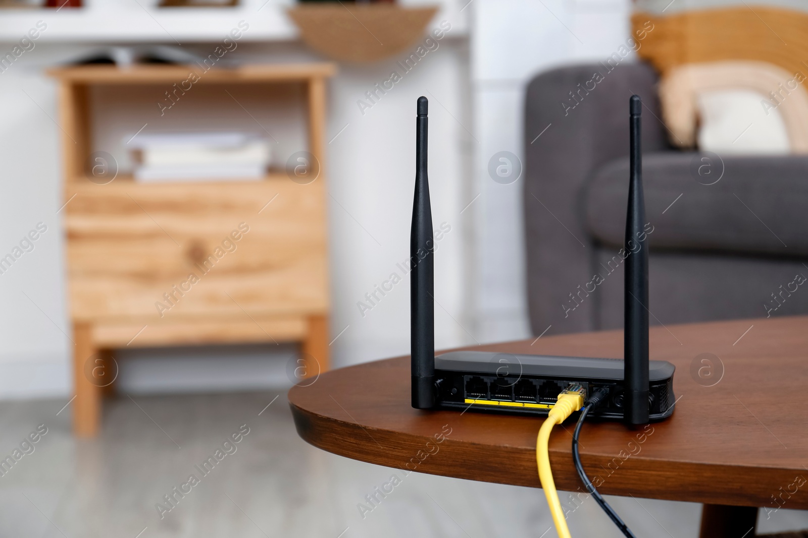 Photo of Modern Wi-Fi router on wooden table indoors. Space for text