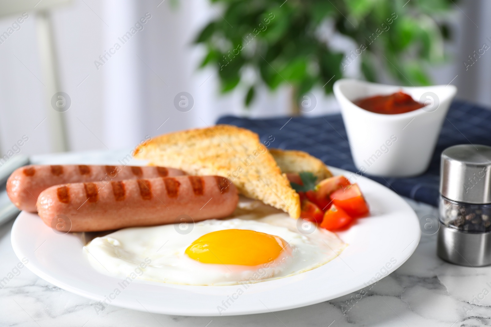 Photo of Tasty breakfast with fried egg and sausages served on white marble table indoors