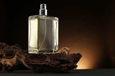 Photo of Luxury men`s perfume in bottle on grey table against dark background, space for text