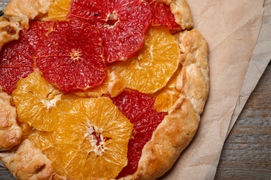 Delicious galette with citrus fruits on wooden table, closeup