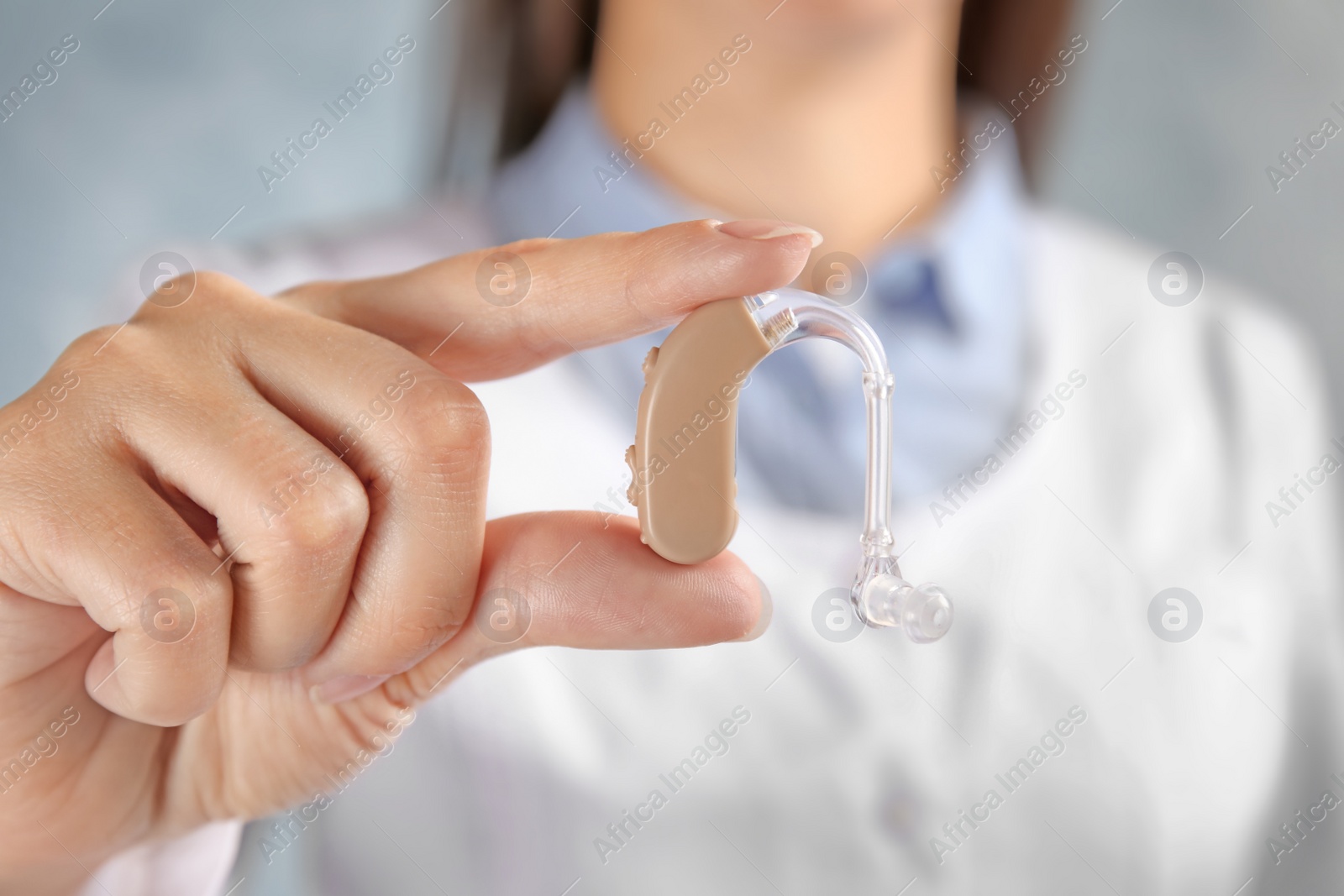Photo of Doctor in white coat with hearing aid, closeup