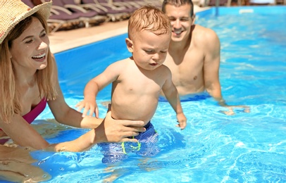 Photo of Happy family with little child resting in swimming pool outdoors