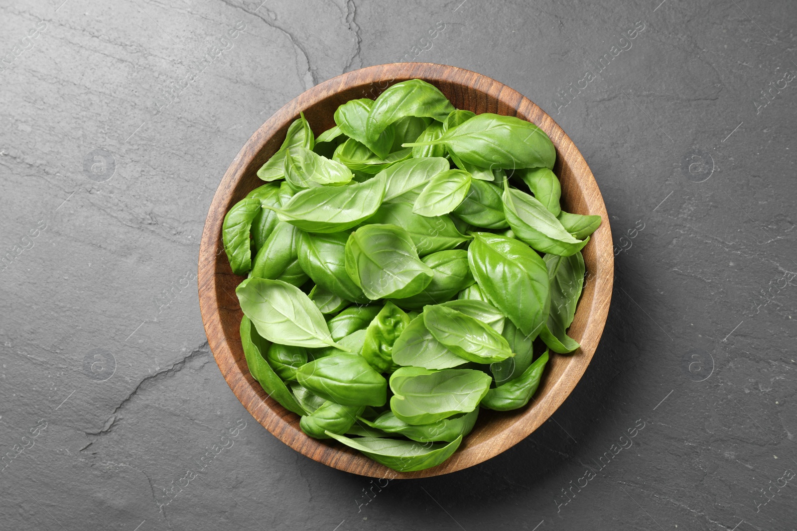 Photo of Fresh basil leaves on grey table, top view