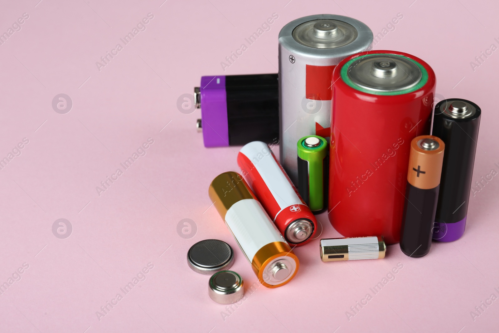 Image of Different types of batteries on pink background, space for text