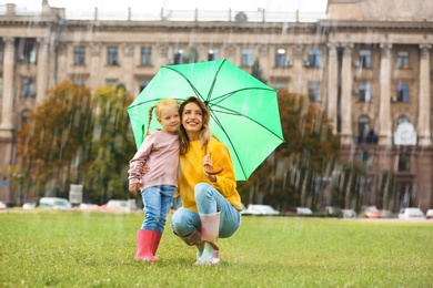 Happy mother and daughter with umbrella in park