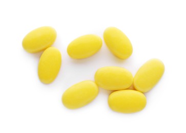 Photo of Tasty yellow dragee candies on white background, top view