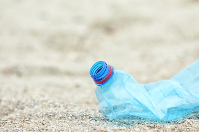 Used plastic bottle on beach, closeup with space for text. Recycling problem