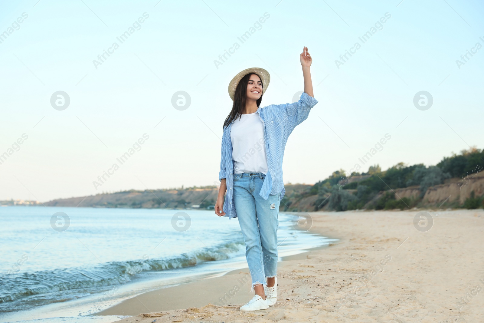 Photo of Beautiful young woman in casual outfit on beach