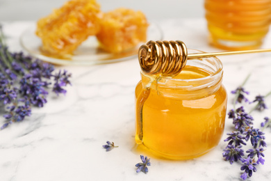 Photo of Tasty honey and lavender flowers on white marble table, closeup