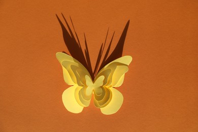 Photo of Yellow paper butterflies on orange background, top view