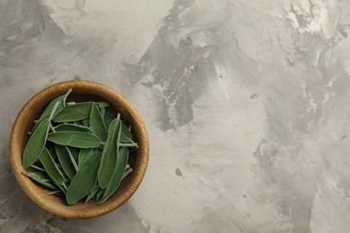 Photo of Fresh green sage in wooden bowl on grey table, top view. Space for text