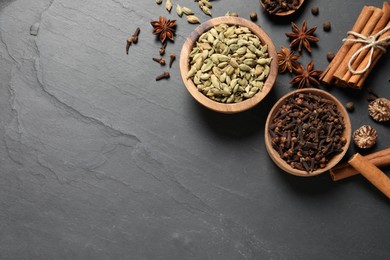Photo of Different spices in bowls on dark gray textured table, flat lay. Space for text