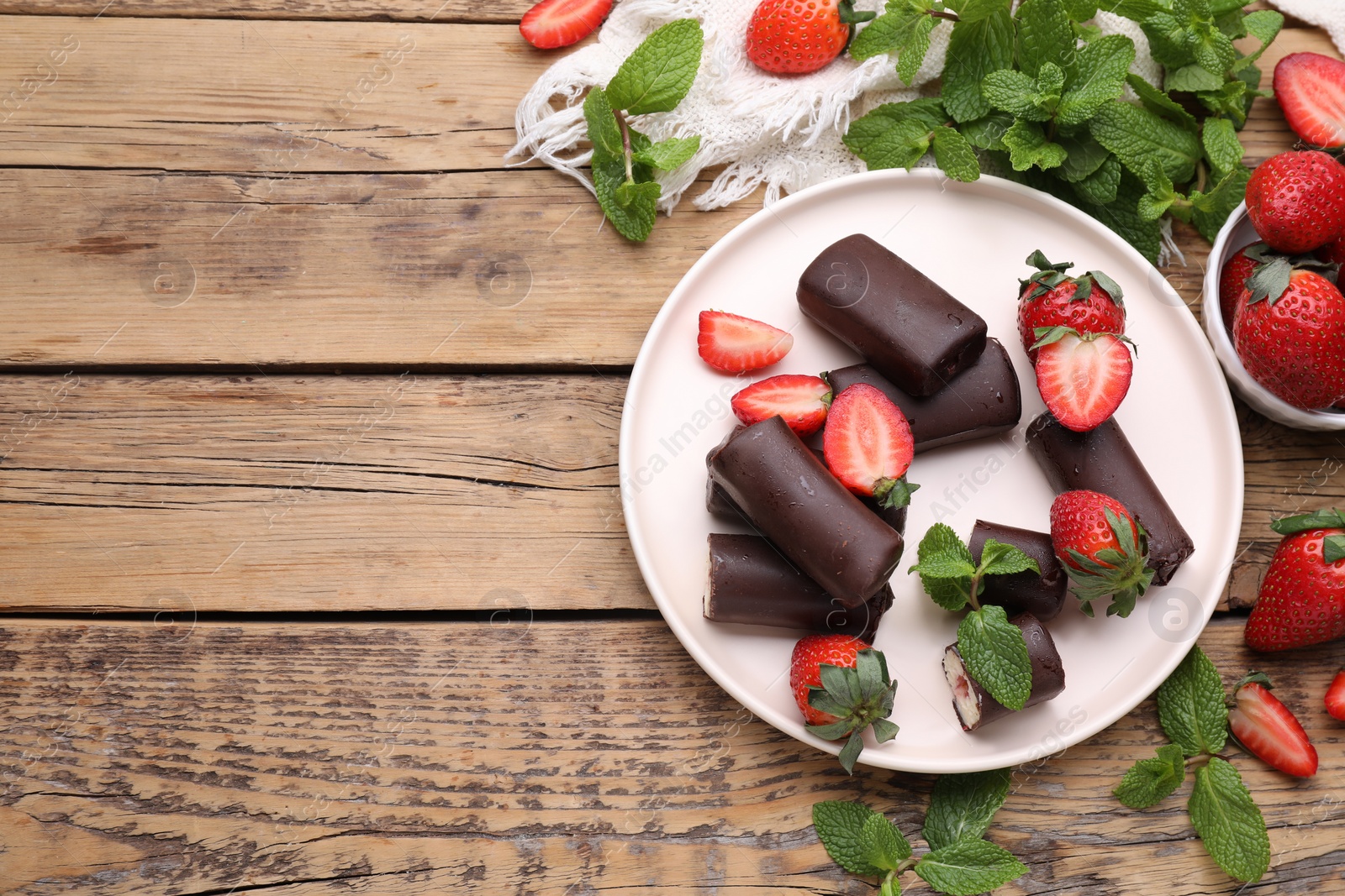 Photo of Delicious glazed curd snacks with fresh strawberries and mint on wooden table, flat lay. Space for text